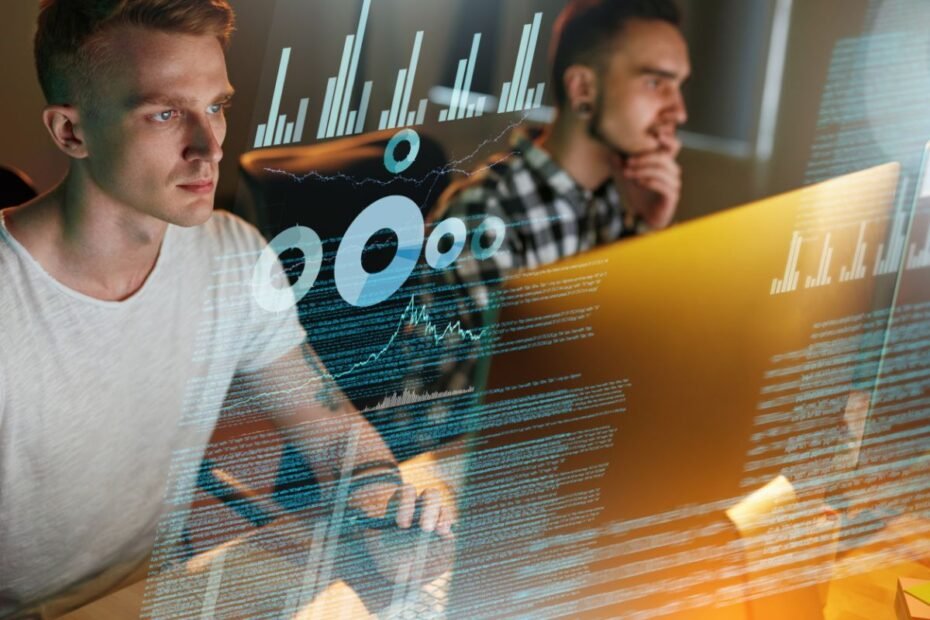 Dois programadores trabalhando em computadores com sobreposição de código e gráficos digitais.