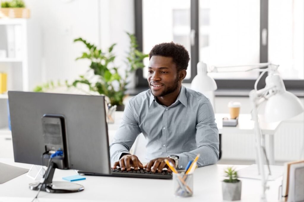 Homem negro sorridente em reunião virtual com colegas, mostrando conexão.