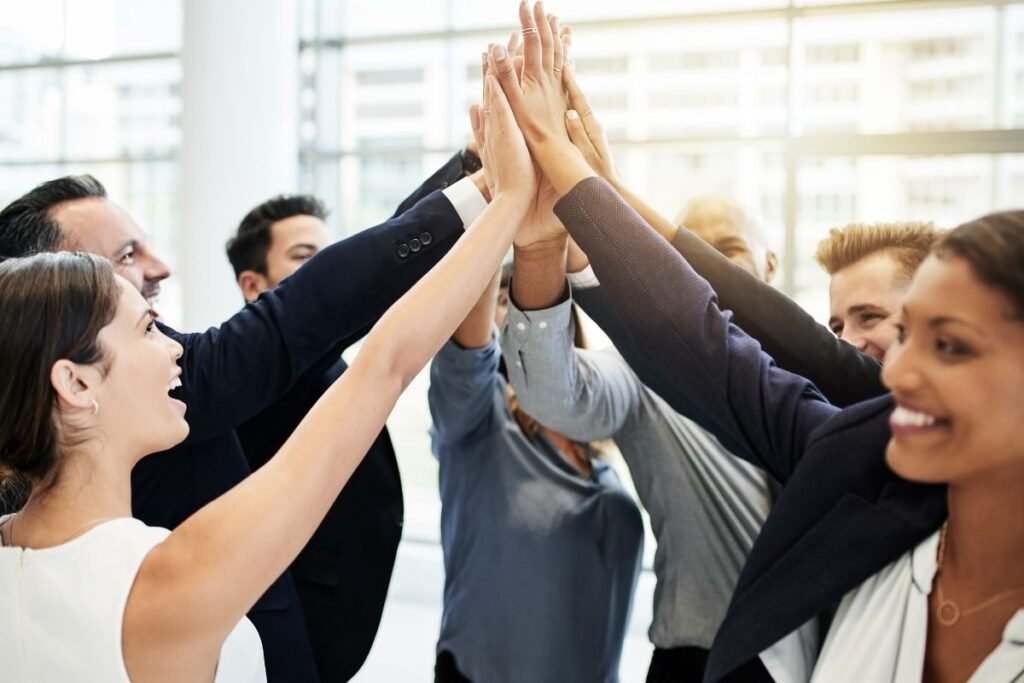 Grupo de colegas de trabalho diversos fazendo um "high five" em círculo.