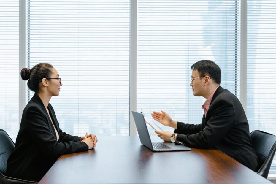 Mulher profissional em traje executivo durante entrevista de emprego com recrutador em escritório moderno
